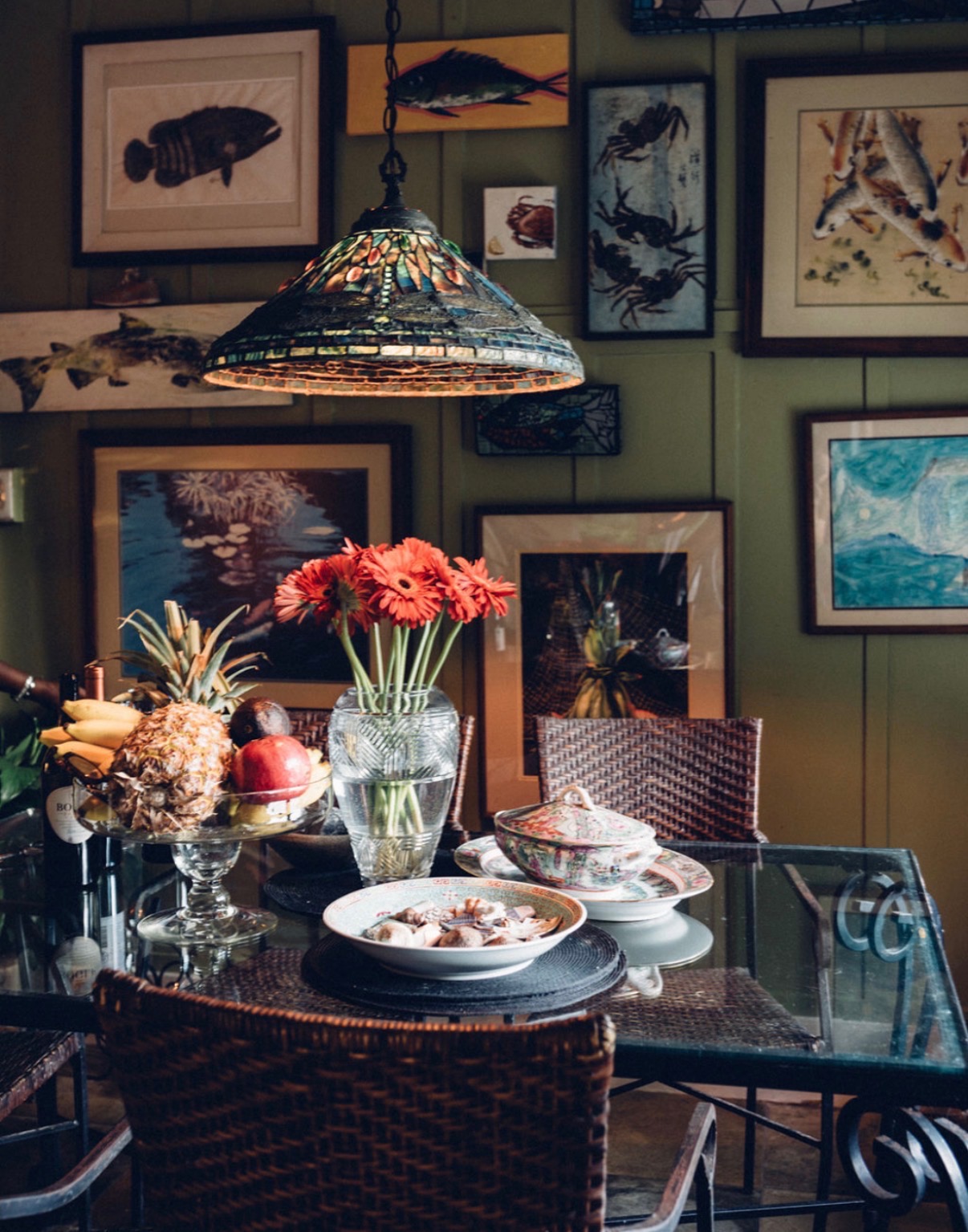 Mosaic lamp glowing above a table set with tropical fruit and fresh flowers